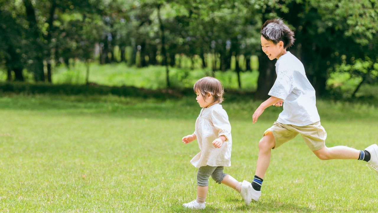 公園を走る赤ちゃんと男の子